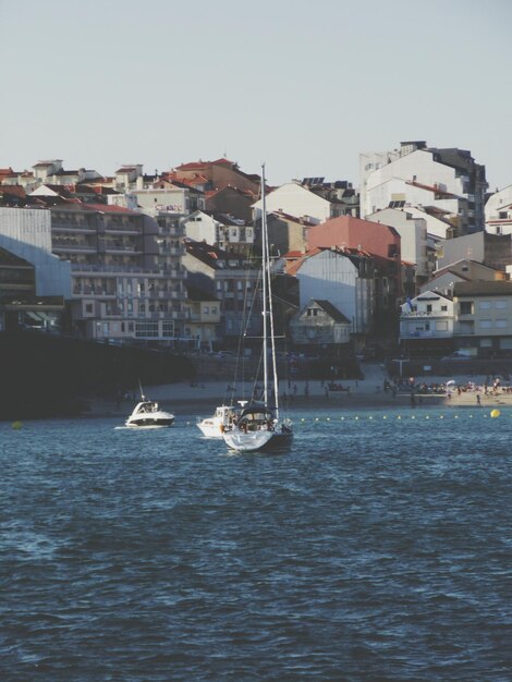 Barcos de vela en la orilla del mar por paisaje urbano