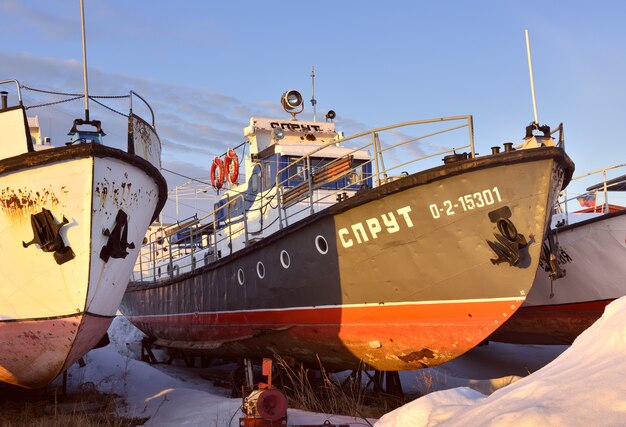 Barcos y yates invernando en la orilla entre los ventisqueros