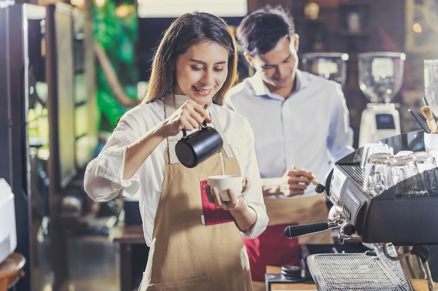 Barista asiática preparando una taza de café, espresso con café con leche o capuchino para el pedido del cliente en la cafetería.