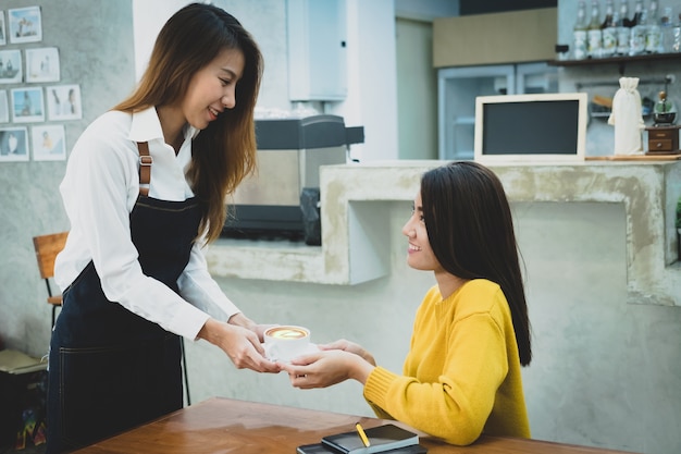 Barista asiático que sirve una taza de café al cliente