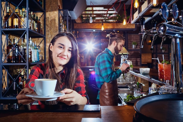 Foto barista barkeeper mädchen hält tasse kaffee in einer bar