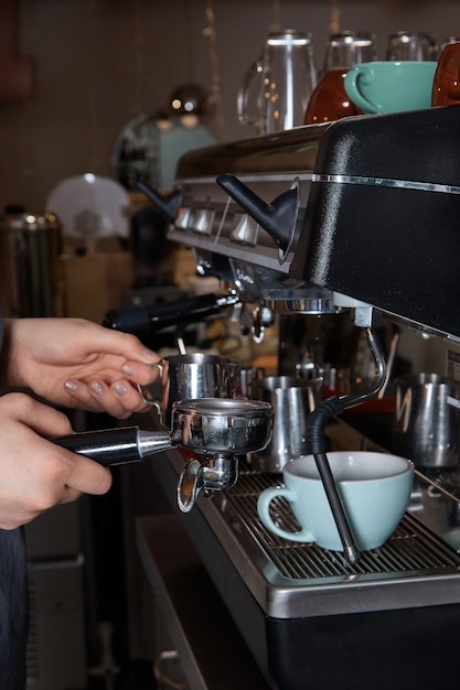 Barista bereitet Kaffee zu und gießt ihn in eine Tasse auf der Kaffeemaschine, Nahaufnahme, Hände einer Frau, verschwommene Oberfläche