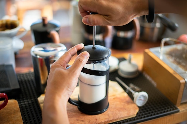Foto barista bombea y agita la leche para obtener espuma al mezclar café con leche