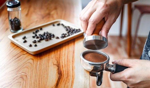 Barista cafe haciendo café con prensas manuales café molido usando tamper en la barra de mostrador de madera