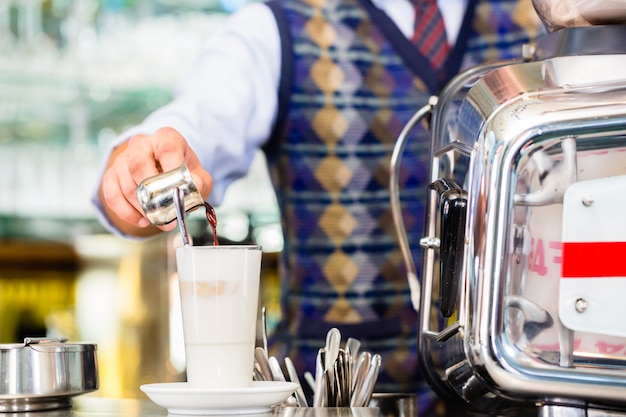 Barista en café vertiendo espresso en latte macchiato