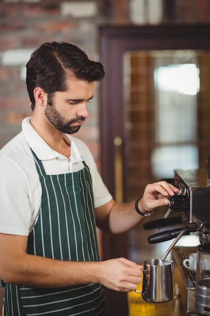 Barista com leite a vapor na máquina de café