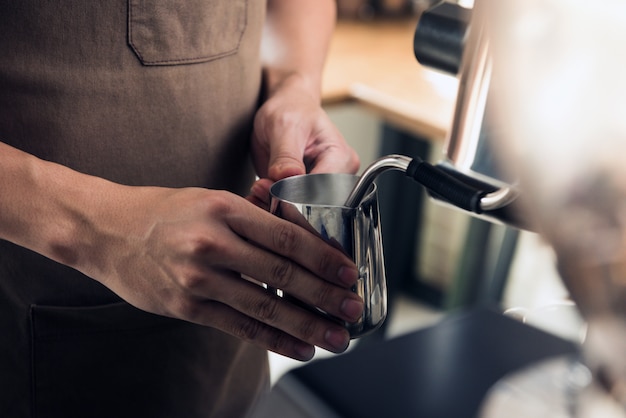 Barista cozinhar leite com máquina de café