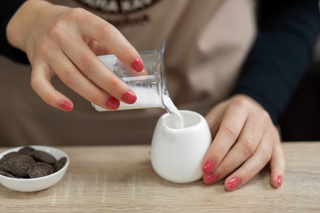 Barista de avental derrama o leite em uma xícara. barista trabalha em uma cafeteria