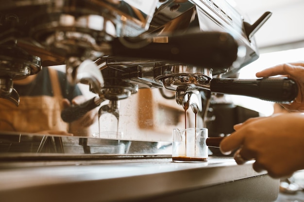 Barista de foco seletivo fazendo café com máquina profissional Café derramando em uma xícara pequena empresa startup