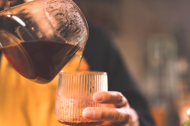 Barista de hipster asiático trabalhando para fazer um café por filtro de café de processo de barra lenta ou fermentação por gotejamento é uma bebida quente de estilo vintage com cafeína de aroma fresco e serve sobre aromático preto escuro