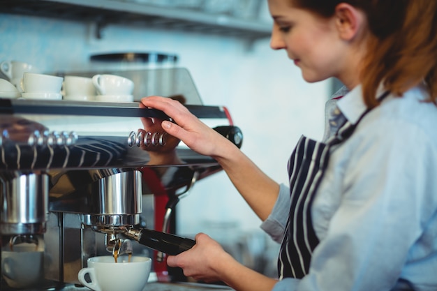 Barista, der Espressomaschine verwendet, um Kaffee in der Schale zu gießen