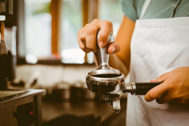 Barista, der frischen Kaffee drückt, mahlt