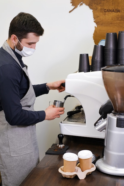 Barista, der Kaffee in Tassen zum Mitnehmen im Coffeeshop in Maske serviert