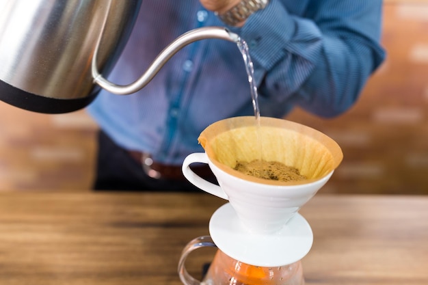 Barista derramando água no filtro de café