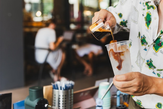 Foto barista derramando café em vidro e preparando café gelado para o cliente