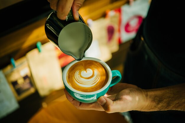 Foto barista derramando leite na xícara de café.