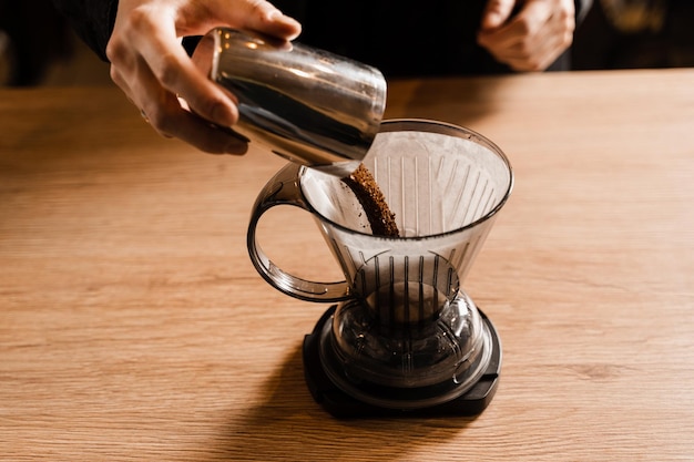Barista despeje o café moído sobre o filtro de papel no gotejador de café inteligente antes de derramar a água da chaleira Processo de preparo despeje sobre o filtro gotejador de café inteligente no café
