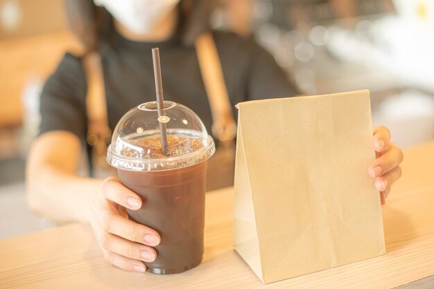 Barista em avental e máscara facial em pé atrás do balcão pronto para dar serviço de café na loja