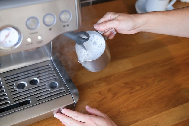 Barista espumando leite em uma jarra de cappuccino