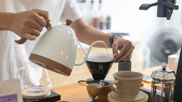 Barista está haciendo café filtrado por goteo con agua caliente y papel de filtro en la cafetería