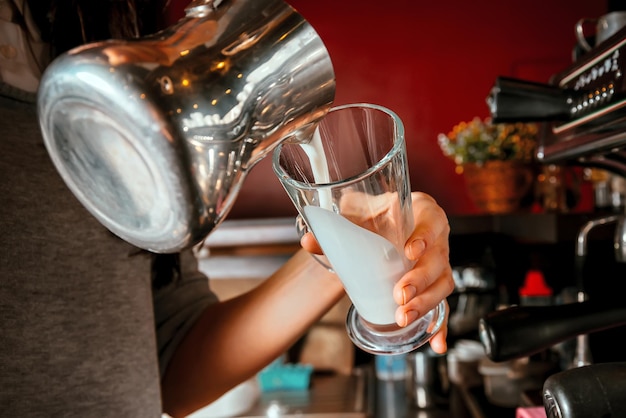 Barista faz café com leite derramando leite em um copo