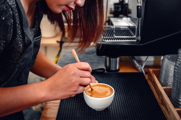 Barista fazendo café a mão de um barista com uma colher de pau fazendo ou preparando espuma de café