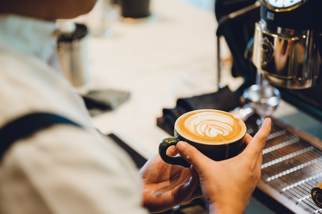 Barista fazendo latte art, tiro foco em xícara de leite e café