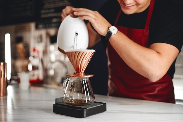 Barista fazendo um gotejamento de café, derramando água quente da chaleira sobre o café