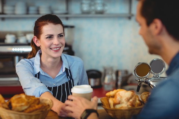 Barista feliz oferecendo café ao cliente no café