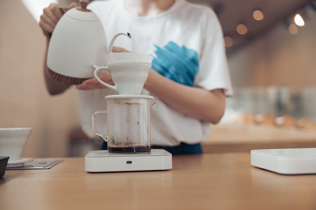 Barista femenina haciendo café de filtro en la cafetería.