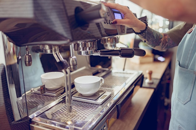 Barista femenina usando una máquina de café en la cafetería