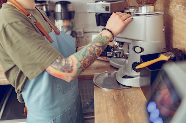 Barista femenina usando una máquina de café profesional en un café