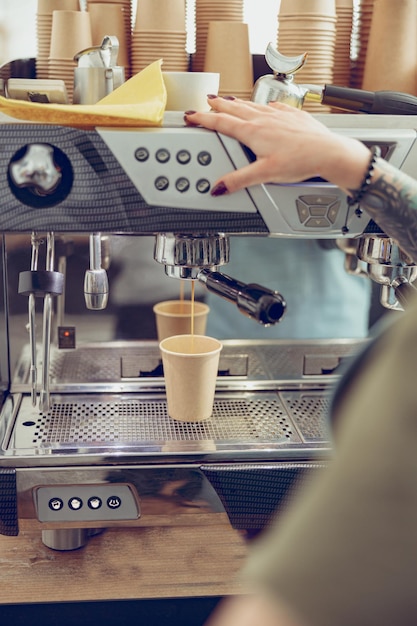 Barista femenina usando una máquina de café profesional en un café