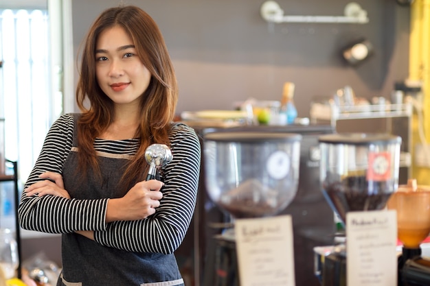 Barista feminina asiática de beleza atraente em frente ao balcão segurando um porta-filtro