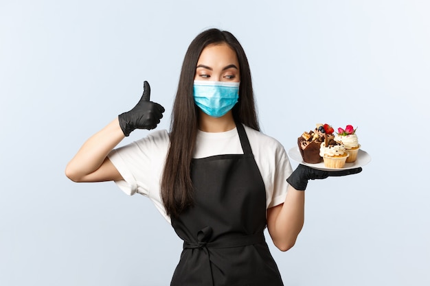 Barista feminino bonito em um avental preto com máscara facial