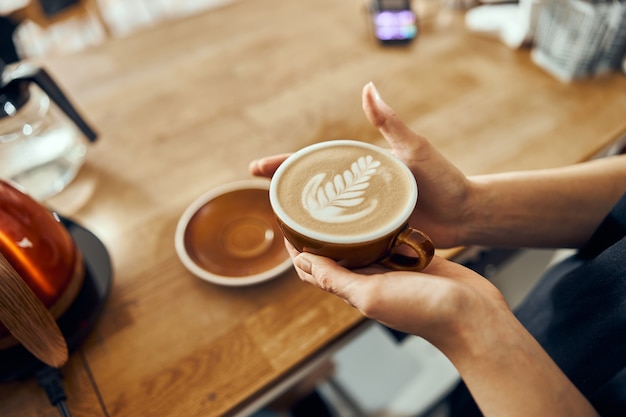 Barista-Frau, die dem Kunden im trendigen Café eine Bestellung aufgibt. Kaffeetasse mit Latte Art.