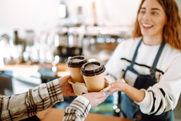 Barista-Frau in einem Café, die Take-Away-Kaffee und Takeaway-Lebensmittel hält