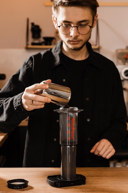 Barista gießt gemahlenen Kaffee über Aeropress, bevor er Wasser aus dem Tropfkessel gießt Prozess des Brühens von Aeropress-Kaffee im Café