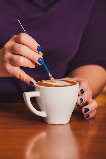 Barista haciendo una taza de café latte art con un dispositivo de metal especial - latte-art pen tool