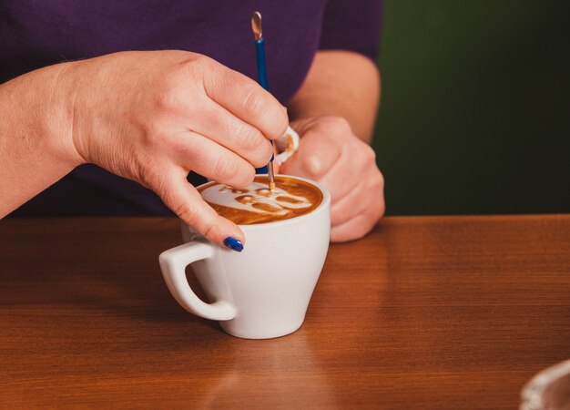 Barista haciendo una taza de café latte art con un dispositivo de metal especial - latte-art pen tool