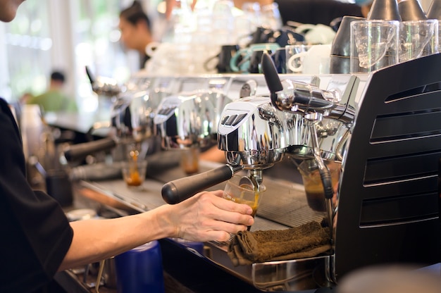 Barista haciendo una taza de café con máquina de café en el café