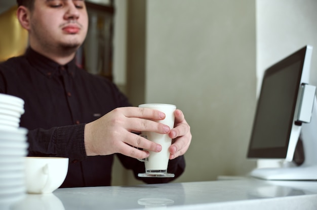 Barista hält eine Tasse Latte hinter die Bar