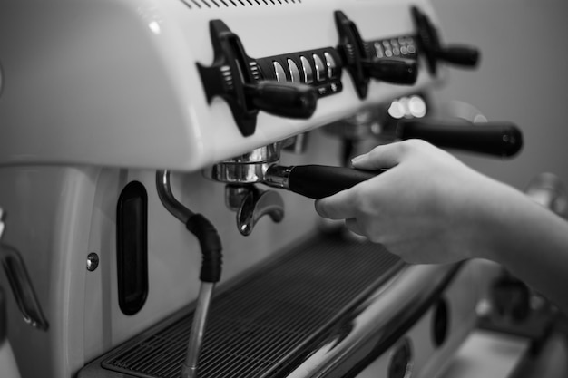 Barista hält einen Halter und macht Kaffee mit einer Doppelboiler-Kaffeemaschine