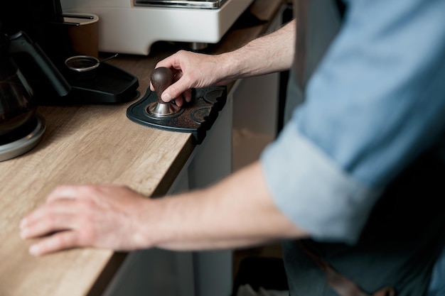 Foto barista hält tamper hinter einem tresen