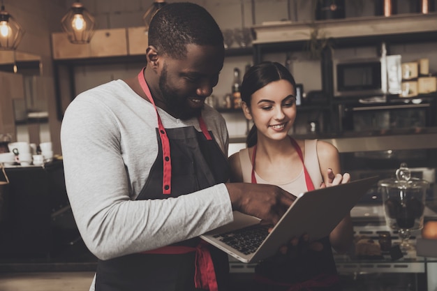 Barista homem e mulher olhando para um laptop