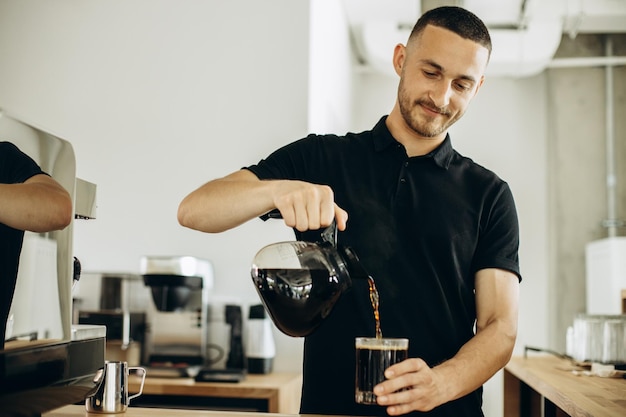 Foto barista in einem kaffeehaus gießt kaffee in ein glas