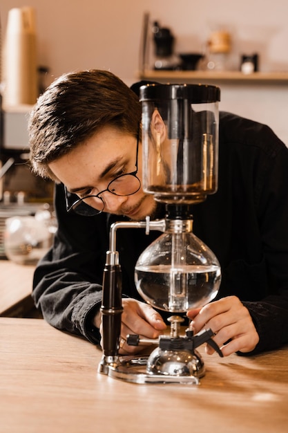Barista ist kochendes Wasser im Siphongerät zum alternativen Brühen von Kaffee Siphon-Vakuumkanne zum Mischen von Kaffee mit kochendem Wasser