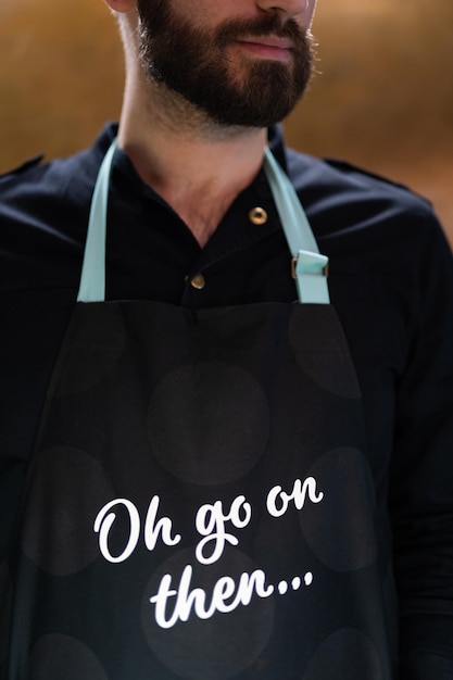 Foto barista-kellner mit bart, nahaufnahme, schwarze schürze mit aufschrift