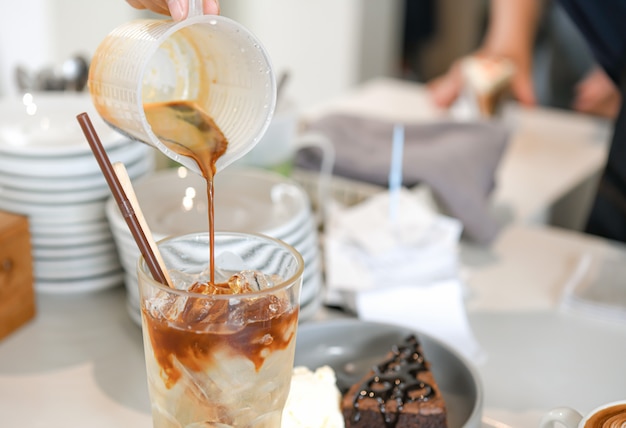 Barista kocht gemischten Kaffee. Er goß Kaffee in ein Glas mit Eis.