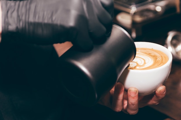 Barista con leche para hacer arte latte de café en la cafetería